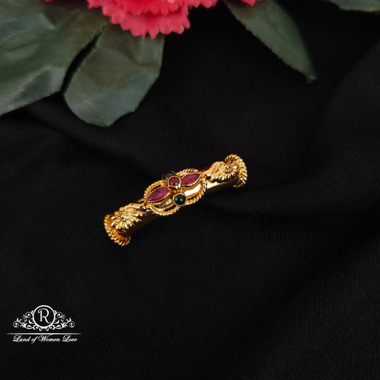 Gold bracelet with red gemstones on a black fabric background